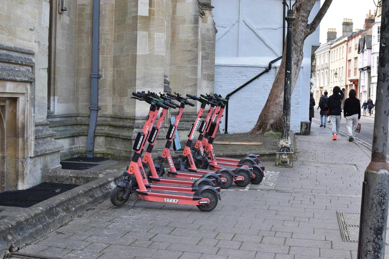 Samuel isaacs bwz1ouvyim8 unsplash A row of red scooters parked on the side of a street